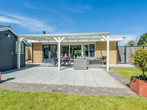 A covered patio area with outdoor furniture and a brick wall. - Holiday Home in Renesse With Swimming Pool (Renesse)