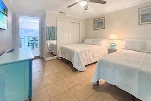 Habitación de hotel con dos camas, un escritorio, un ventilador de techo y vistas al exterior.