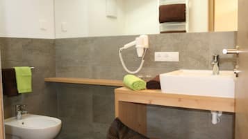 A bathroom with a sink, a hairdryer, a towel, and a bidet.