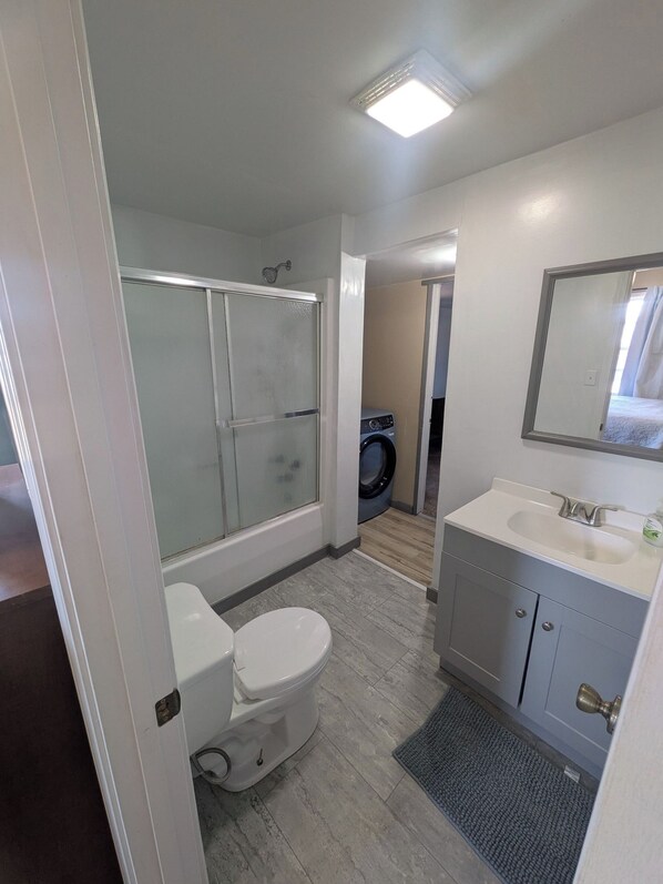A bathroom with a toilet, a sink, a mirror, and a shower. - Centrally Located 2-bedroom house in Robinson (Robinson)