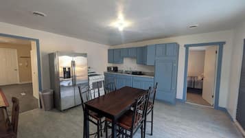 A spacious kitchen with a central island, a dining area with a dark wooden table and chairs, and light blue cabinetry.