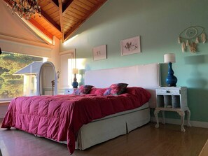 Ein Schlafzimmer mit einem Bett, einem Nachttisch, einer Lampe und Wandbildern.