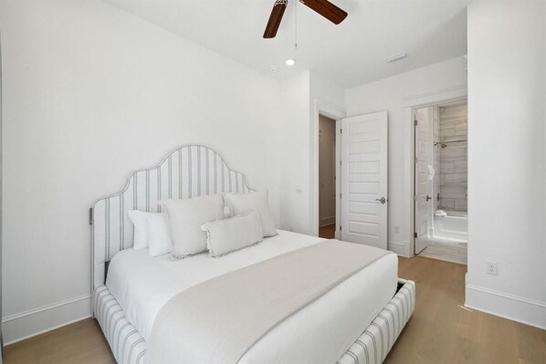 A bedroom with a large bed, a ceiling fan, and a walk-in closet. - The Sandcastle at Bluewater Landing (Santa Rosa Beach)