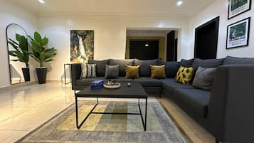 Una sala de estar moderna con un sofá seccional, una mesa de centro y una planta grande en maceta.