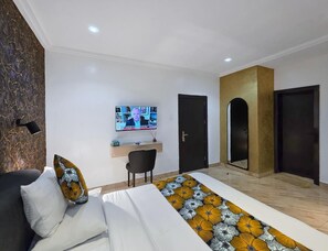 Una moderna camera d'albergo con un letto, una scrivania, una TV e una porta.