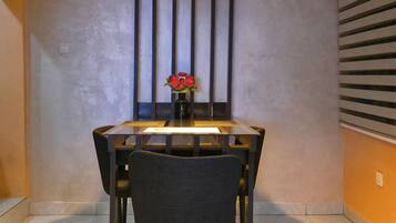 A dining area with a table, chairs, a pendant light, and a vase with flowers.