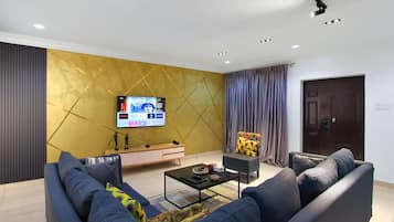 A modern living room with a sofa, a coffee table, a TV mounted on the wall, and a door.