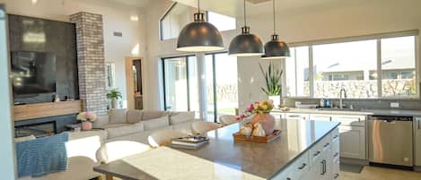 A modern kitchen with a central island, built-in appliances, and pendant lighting.