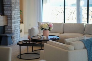 A modern living room with a sectional sofa, a round coffee table, and a fireplace. - The Grand Luxe Retreat (Las Cruces)