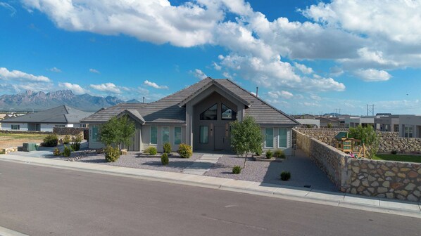A modern two-story house with a stone facade, large windows, and a mountain backdrop. - The Grand Luxe Retreat (Las Cruces)