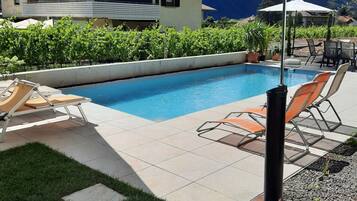 Une piscine avec des chaises longues, une pelouse et une vue sur une montagne.