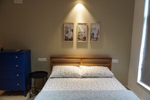Un dormitorio con cama, cómoda, silla y tres cuadros en la pared.