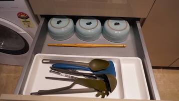 A drawer with kitchen utensils and three containers.