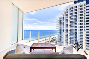 Ein Balkon mit Blick auf einen Strand und ein Hochhaus.