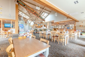 A spacious restaurant with high ceilings, exposed beams, and a variety of seating arrangements including tables and booths.