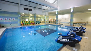 An indoor swimming pool with Yamaha watercraft, tiled walls, and a clear water sign.