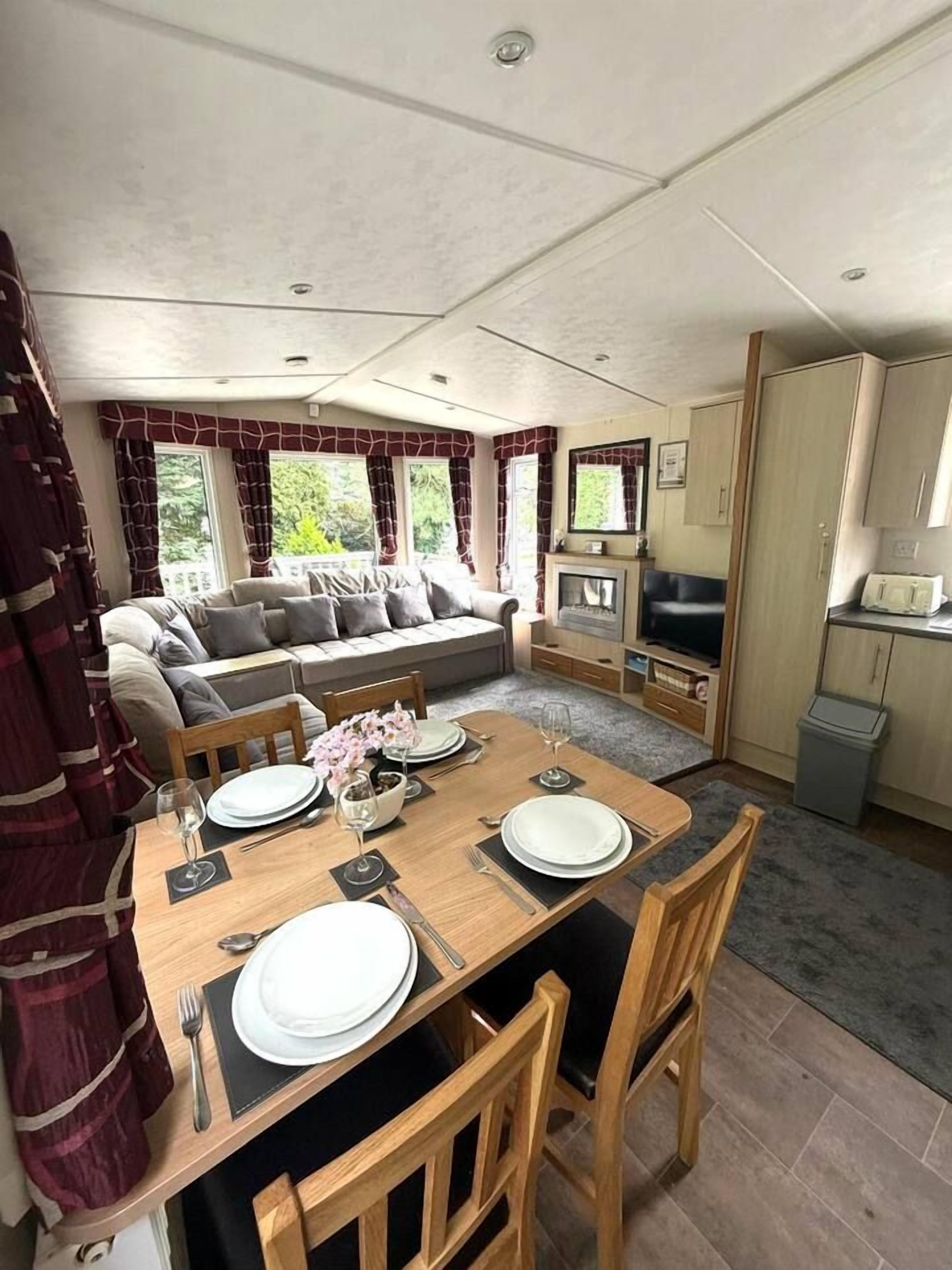 Un espace de vie compact comprenant un coin repas, un canapé, un téléviseur et une kitchenette.