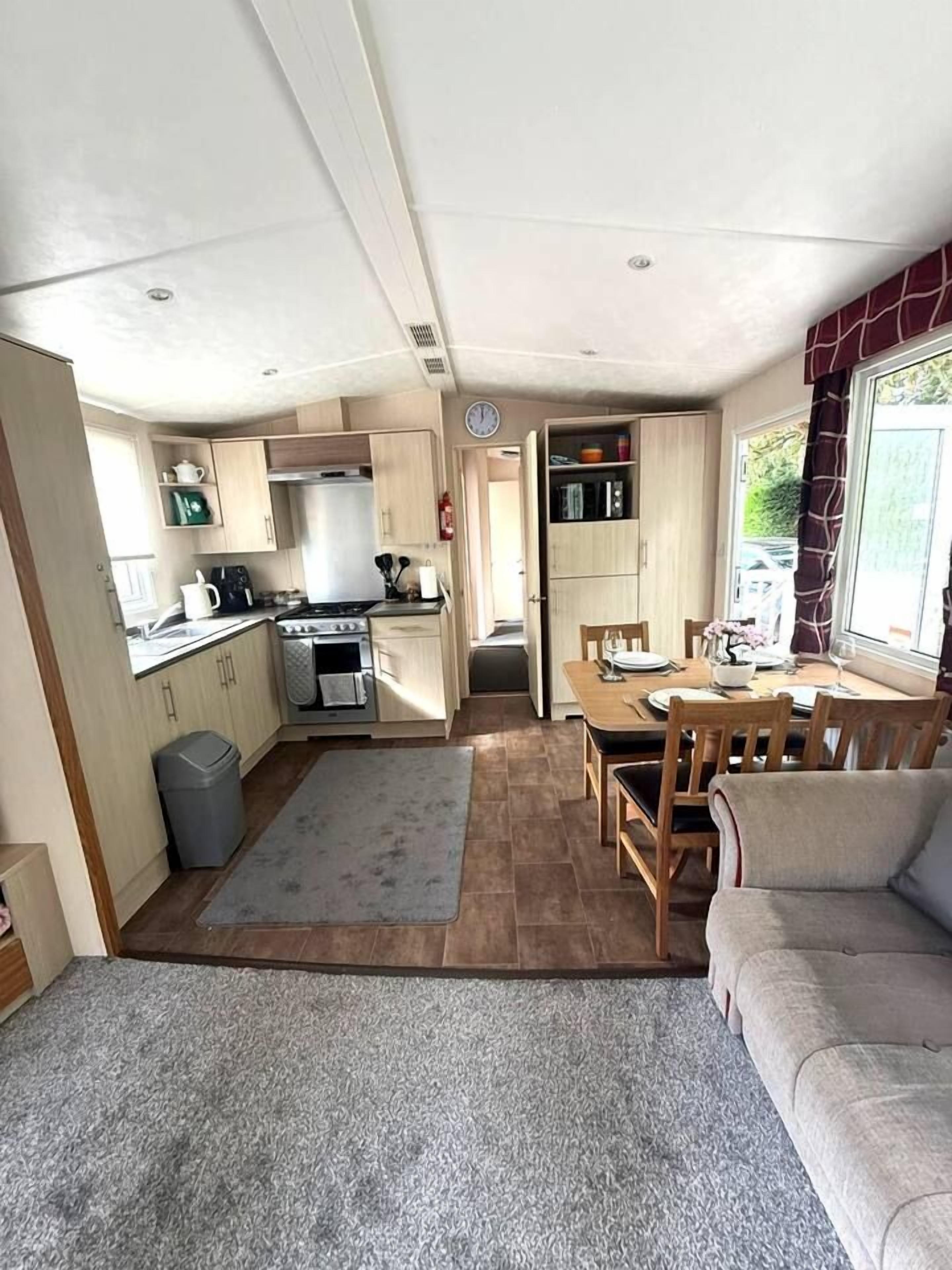 A compact kitchen with a dining area, a sofa, and a rug.