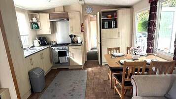 A compact kitchen with a dining area, a sofa, and a rug.