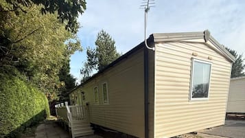 A single-story mobile home with a window, a door, and a small porch area.