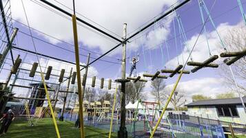An outdoor adventure course with ropes, poles, and a fenced area.