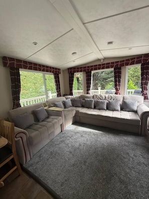 Una habitación con un amplio sofá modular en forma de L, una mesita y vistas a zonas verdes.