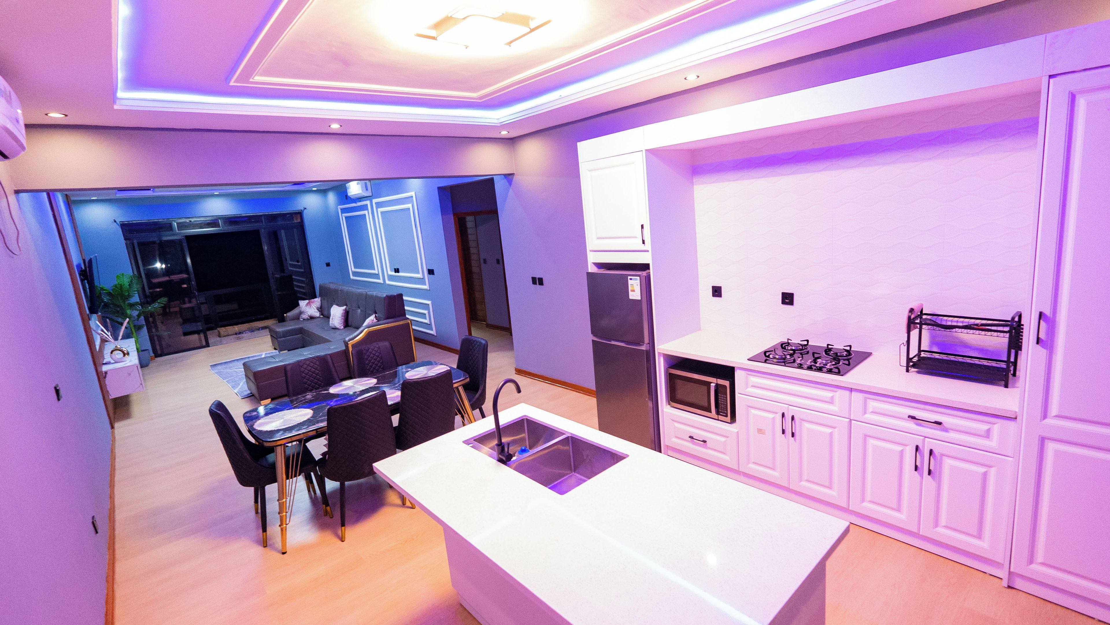 A modern kitchen with a central island, built-in appliances, and a dining area with a sofa and chairs.