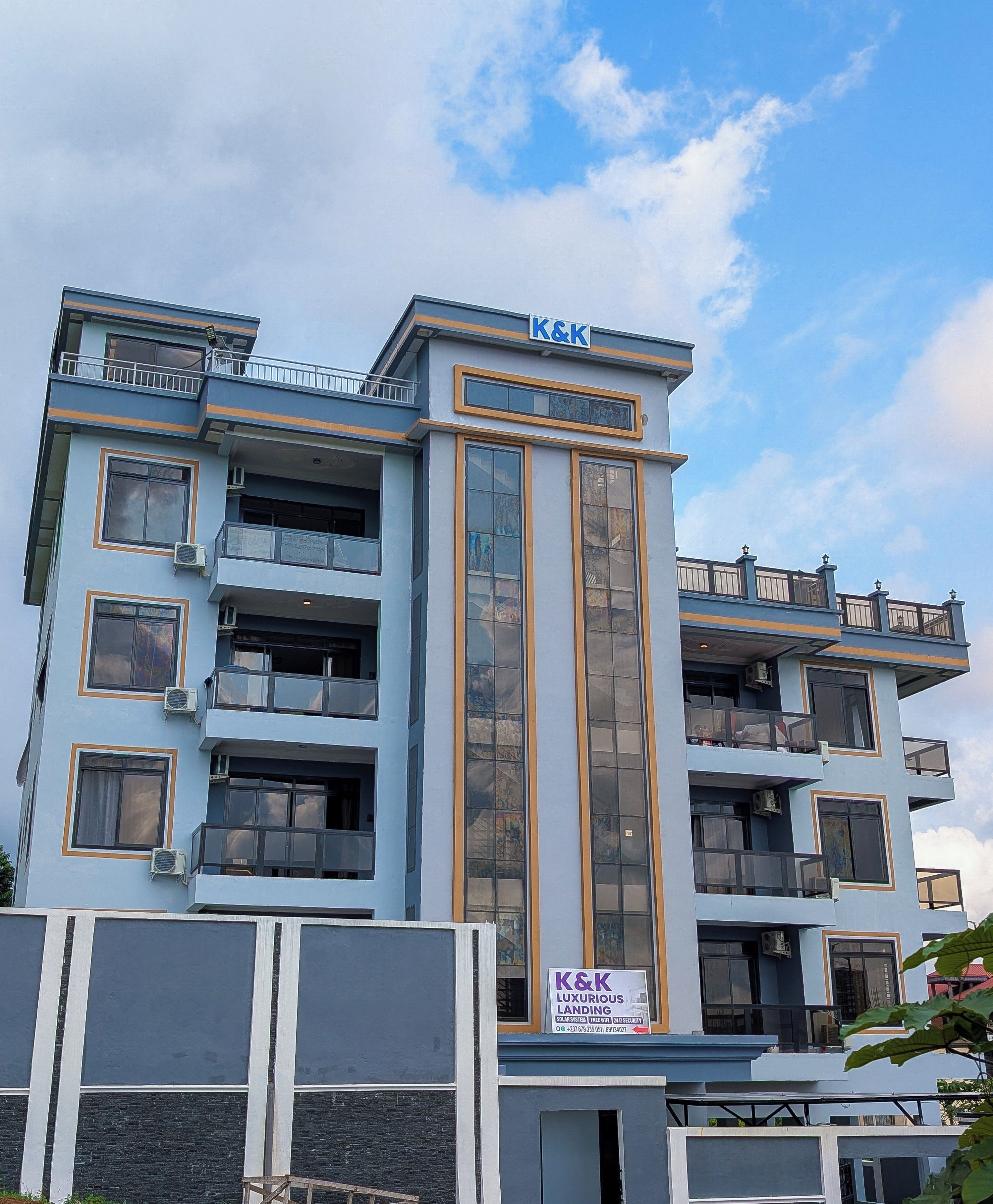 A multi-story building with balconies, air conditioning units, and a sign indicating 'K&K LUXURIOUS LANDING'.