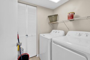 A laundry room with two washing machines, a basket, and a shelf with a can. - 3BR Oceanfront Escape - Cherry Grove Views (North Myrtle Beach)