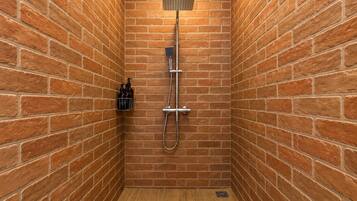 A small, enclosed shower area with a wooden floor and a metal showerhead.