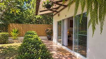 A modern house with a wooden deck, a hanging flower pot, and a glass door leading to a bedroom.