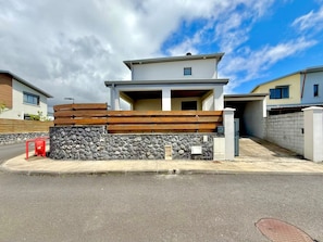 A modern two-story residential building with a stone and wooden facade, a covered porch, and a gated entrance. - La Villa des Rochers, Calm, Modern and Mountain (Bras-Panon)