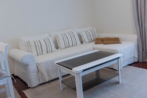 A white sofa with striped pillows, a white coffee table, and a brown throw blanket. - Formosa Beach Apartment Vista Mar a 2 Minutos da Praia (Funchal)