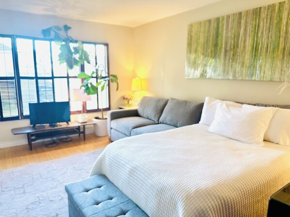 Une chambre à coucher comprenant un lit, une télévision, un bureau et une fenêtre avec des stores.