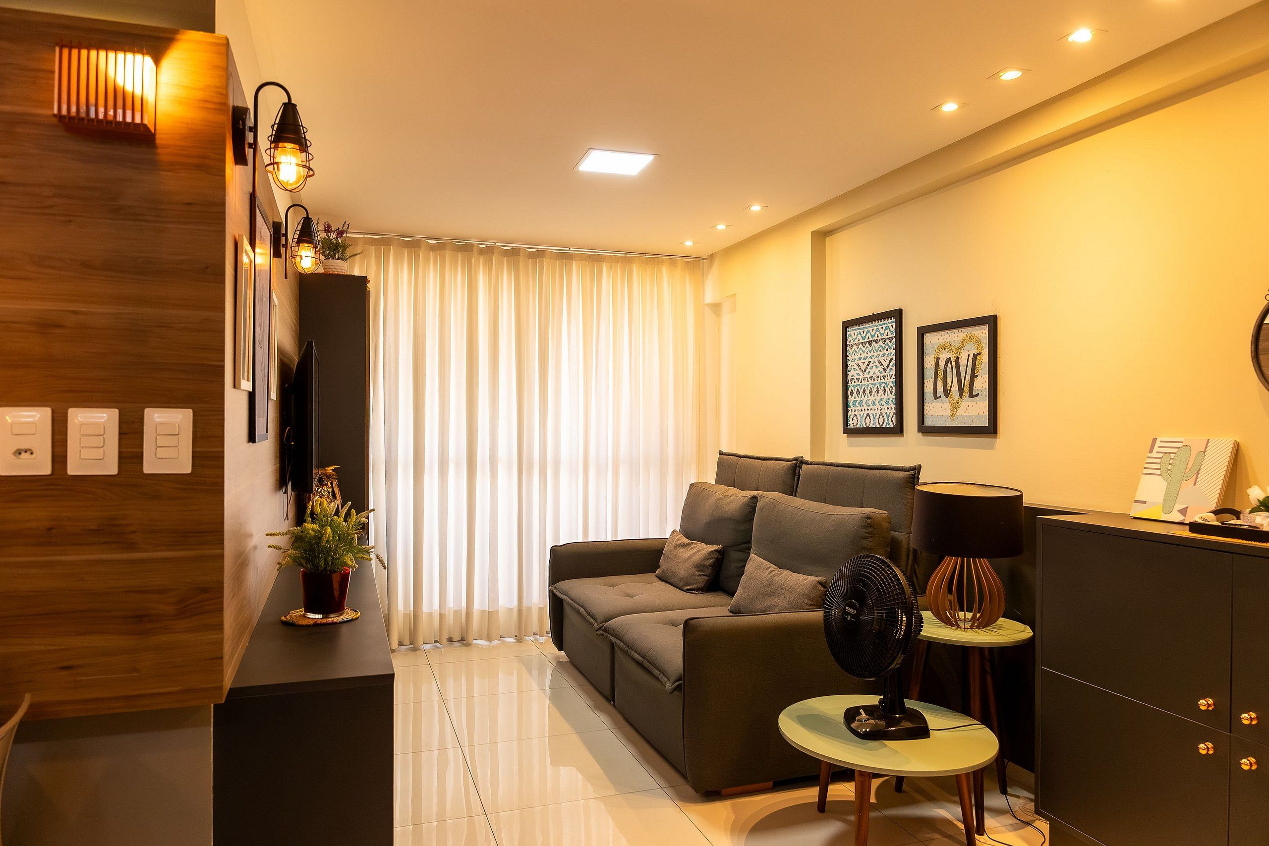 Un salon moderne avec un canapé, une petite table, un ventilateur et une lampe décorative.