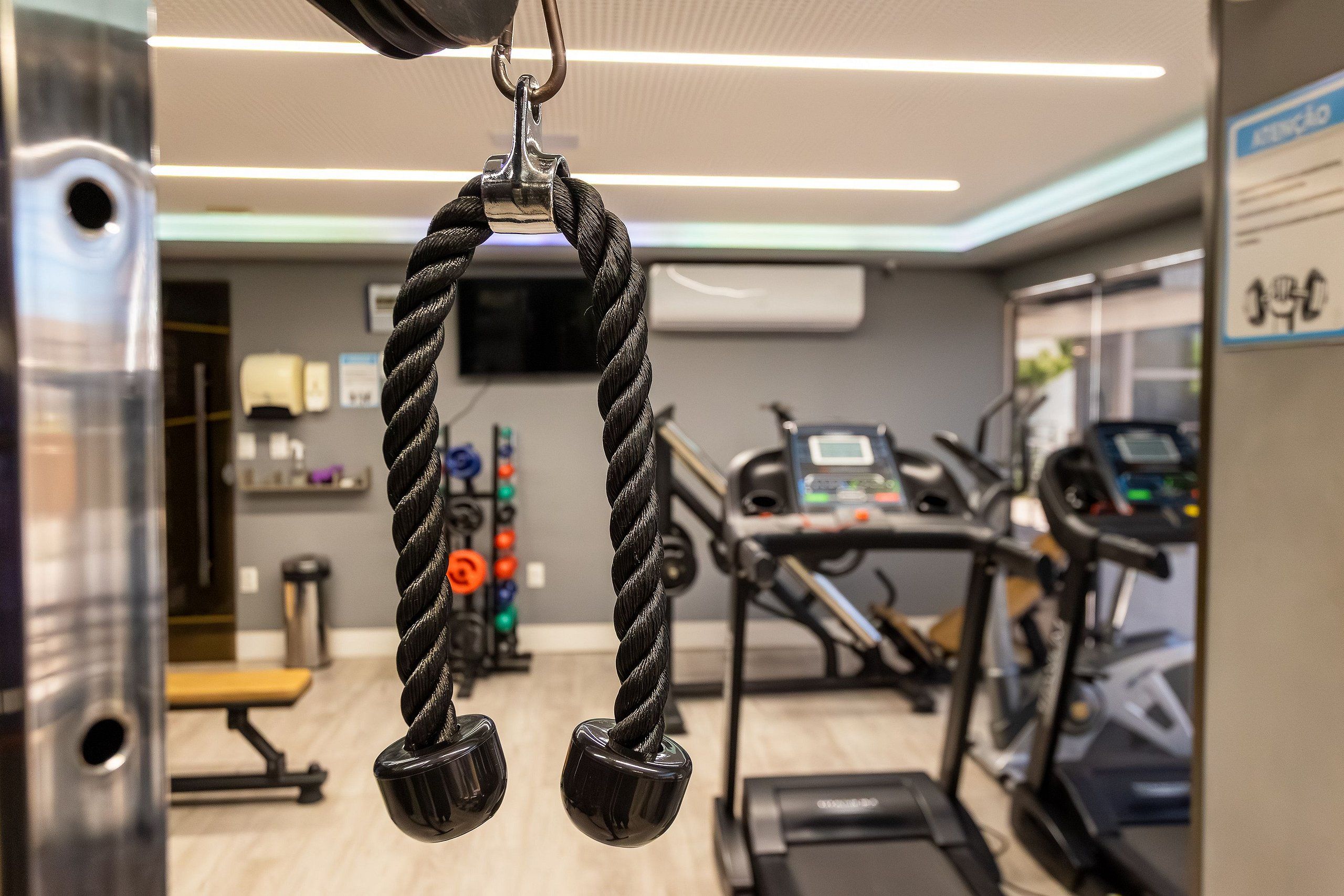Une salle de sport équipée de matériel d'exercice, notamment une machine à câbles et des tapis de course.