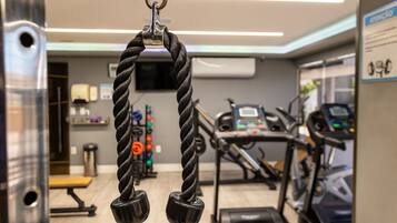 Un gimnasio con equipo de ejercicio, incluyendo una máquina de poleas y cintas de correr.
