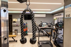 Un gimnasio con equipo de ejercicio, incluyendo una máquina de poleas y cintas de correr.