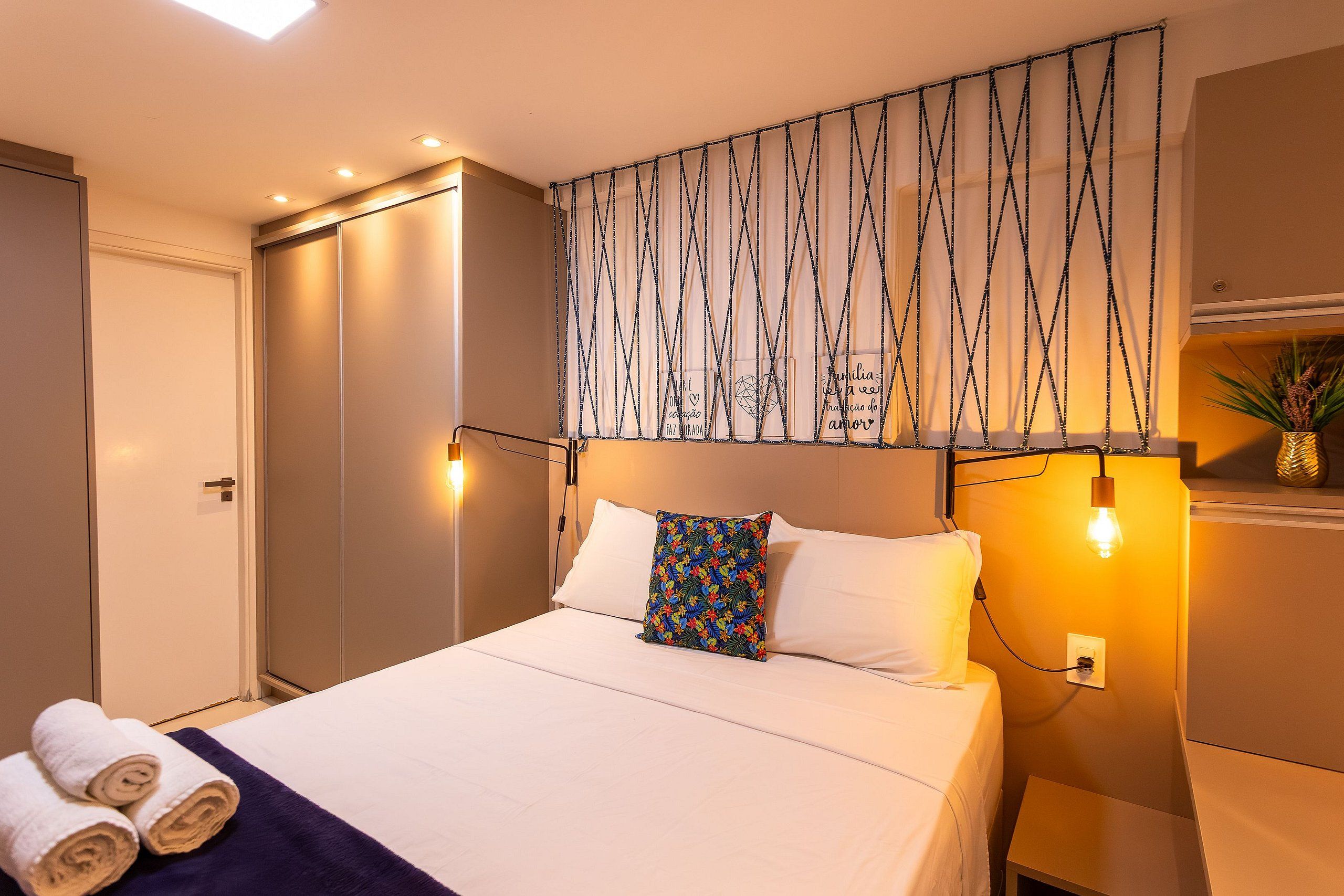 Una habitación de hotel con una cama, una lámpara de pared y una puerta.
