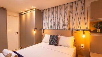 Una habitación de hotel con una cama, una lámpara de pared y una puerta.