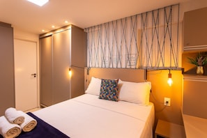 Una habitación de hotel con una cama, una lámpara de pared y una puerta.