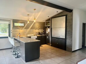 Eine moderne Küche mit Kochinsel, Edelstahlgeräten und einer Wand mit Steinverkleidung.