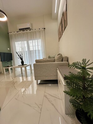 A modern living room with a sofa, a coffee table, a TV, and a potted plant. - CITYCUBE 1 / MODERN MINIMAL STUDIO 5' FROM ARISTOTELOUS SQUARE (Thessaloniki)