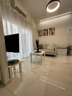 A modern living room with a flat-screen TV, a sofa, a coffee table, and a potted plant. - CITYCUBE 1 / MODERN MINIMAL STUDIO 5' FROM ARISTOTELOUS SQUARE (Thessaloniki)