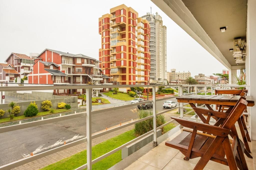 A balcony with a view of a residential area, including a tall apartment building and a street with cars.