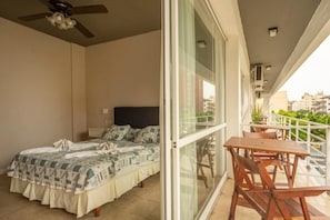 A bedroom with a bed, a ceiling fan, and a balcony with a table and chairs. - Hotel Marítimo (Villa Gesell)