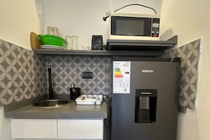 A compact kitchenette with a PHILCO refrigerator, a microwave, a water dispenser, and a sink.