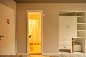 Una habitación de hotel con un armario, una puerta con letrero de prohibido fumar y una cortina.