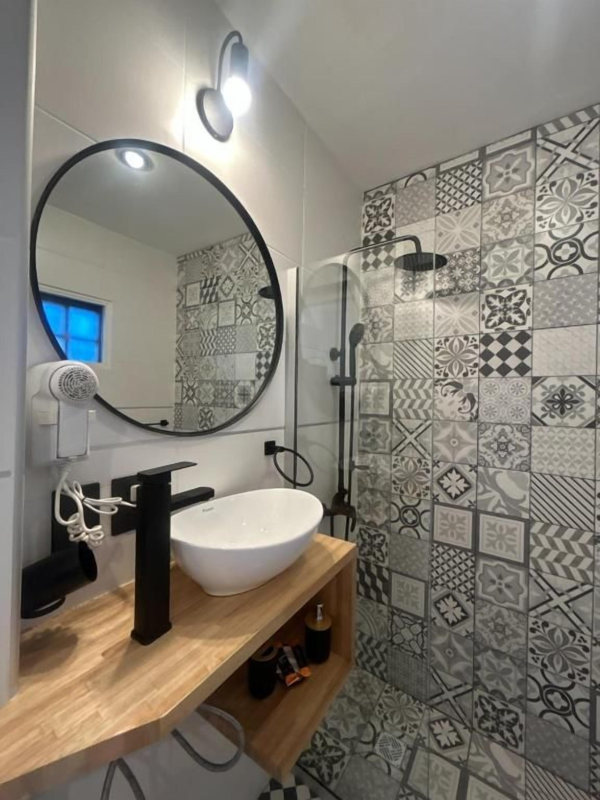 Un baño con un espejo redondo, un lavabo blanco y una zona de ducha.