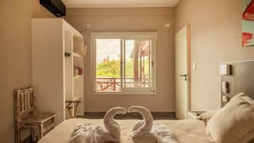 Una habitación de hotel con cama, un banco, una ventana con vistas y una puerta.